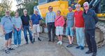 Die Teilnehmer der Lenkungsgruppe stehen vor einem Bagger.