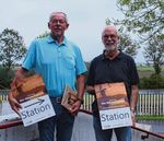 Hans Gerdes und Jürgen Ruge halten Stationsplakate in die Kamera.