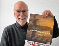 Jürgen Ruge hält ein Werbeplakat des Aktionstages hoch.